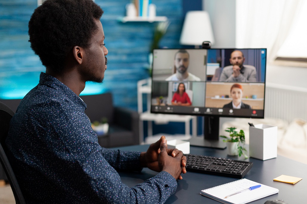 Man of african ethnicity using conference webcam communication Man of african ethnicity using conference webcam communication to connect via internet with coworkers while working from home. Black person remote worker chatting about job duties