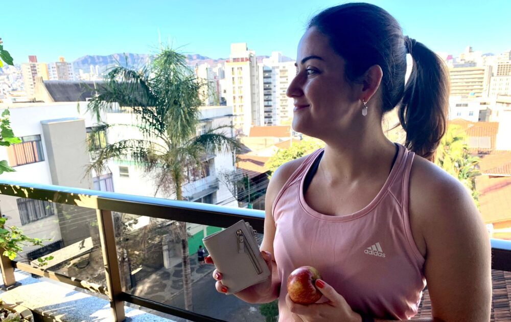 Mulher segurando uma carteira e uma fruta